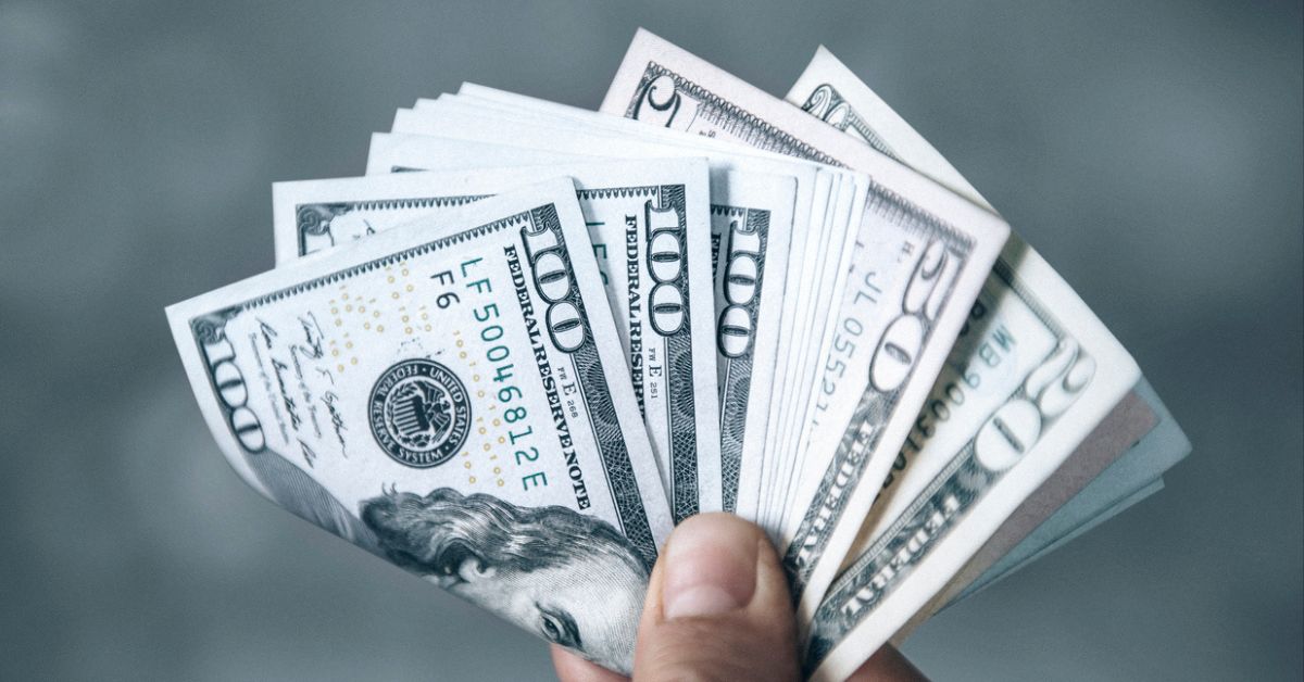 Person holding a handful of $100, $50, and $20 bills